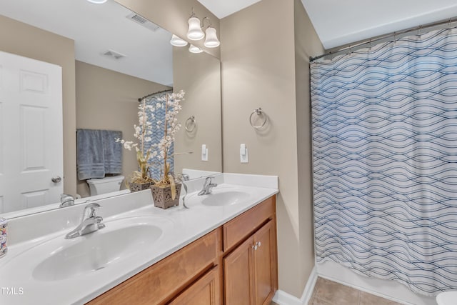 full bath featuring toilet, tile patterned floors, a shower with shower curtain, double vanity, and baseboards