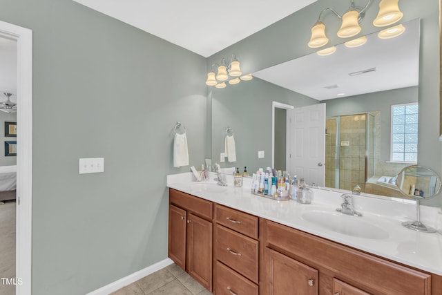 ensuite bathroom with a stall shower, tile patterned flooring, double vanity, and baseboards