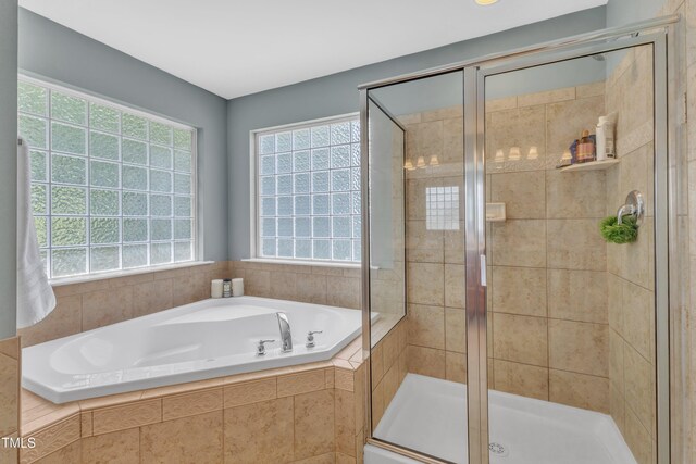 full bath featuring healthy amount of natural light, a shower stall, and a bath