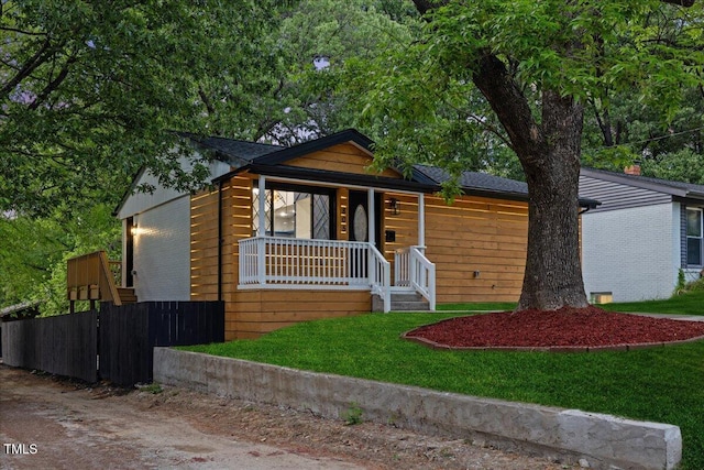view of front of house featuring a porch, a front lawn, and fence