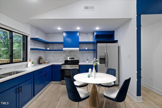 kitchen with open shelves, appliances with stainless steel finishes, light wood finished floors, lofted ceiling, and blue cabinets