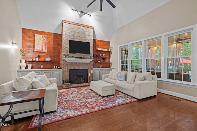 living room featuring a ceiling fan, high vaulted ceiling, wood finished floors, a fireplace, and baseboards