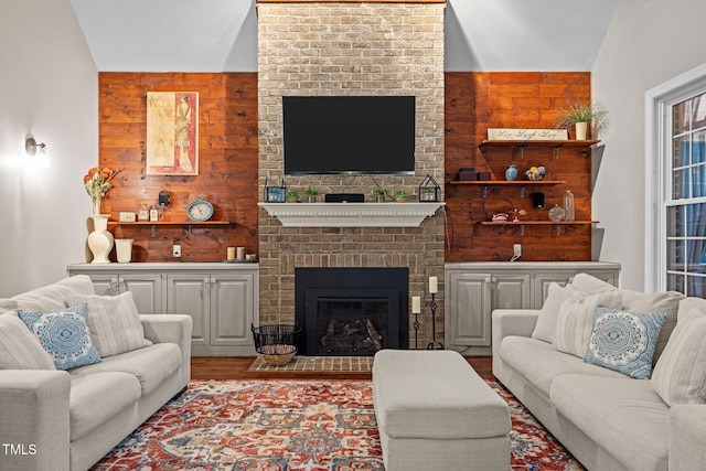 living room with wood walls, a brick fireplace, and wood finished floors