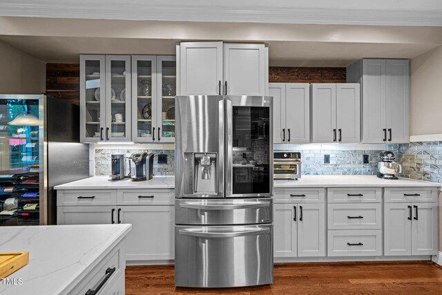kitchen with stainless steel fridge, tasteful backsplash, glass insert cabinets, light stone countertops, and crown molding