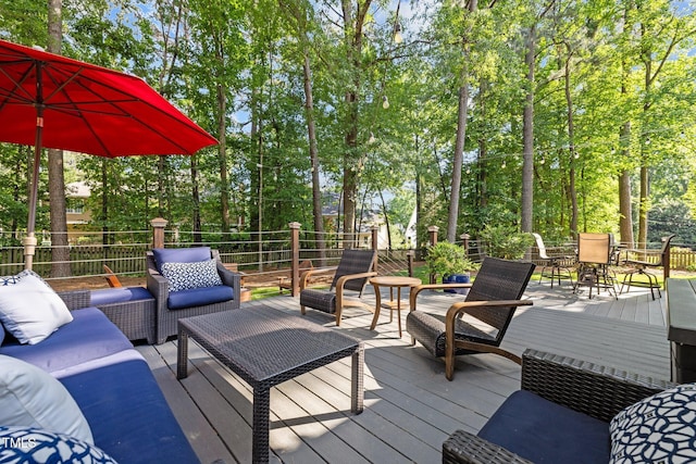 wooden deck with an outdoor hangout area, outdoor dining area, and view of wooded area