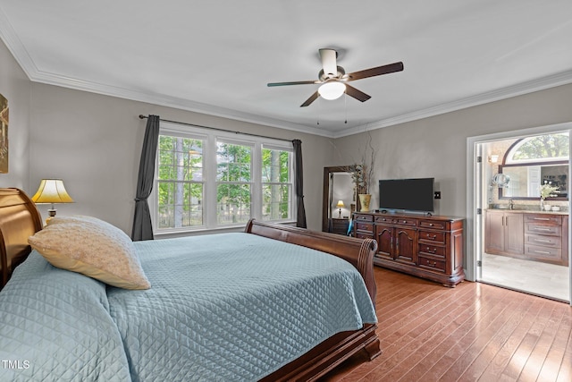 bedroom featuring multiple windows, wood-type flooring, crown molding, ceiling fan, and a sink