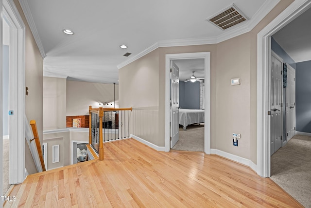 hall featuring an upstairs landing, wood finished floors, baseboards, recessed lighting, and ornamental molding
