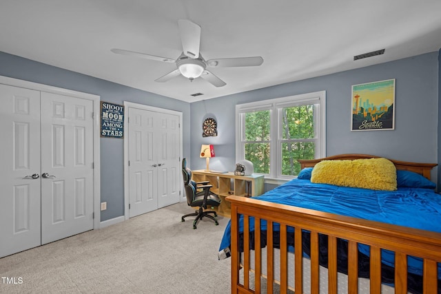 carpeted bedroom with multiple closets, a desk, a ceiling fan, and baseboards