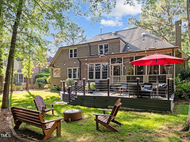 rear view of house with brick siding, a wooden deck, a chimney, and a sunroom