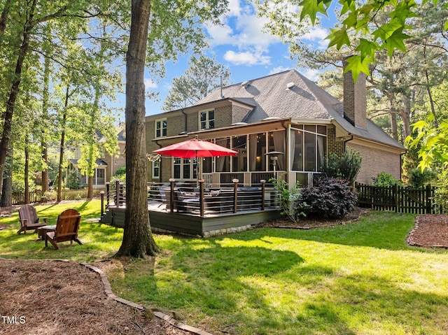 rear view of house featuring a sunroom, a deck, brick siding, a chimney, and a shingled roof
