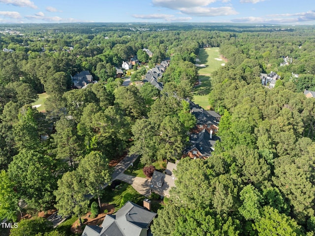 aerial view of property's location featuring a forest and nearby suburban area