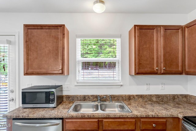 kitchen featuring brown cabinetry, appliances with stainless steel finishes, a healthy amount of sunlight, and a sink