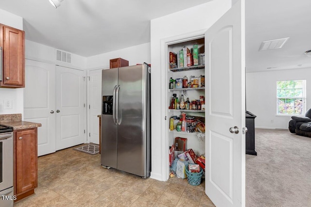 kitchen featuring visible vents, open floor plan, appliances with stainless steel finishes, and brown cabinets