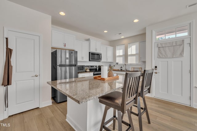 kitchen featuring appliances with stainless steel finishes, light wood-type flooring, visible vents, and a kitchen bar