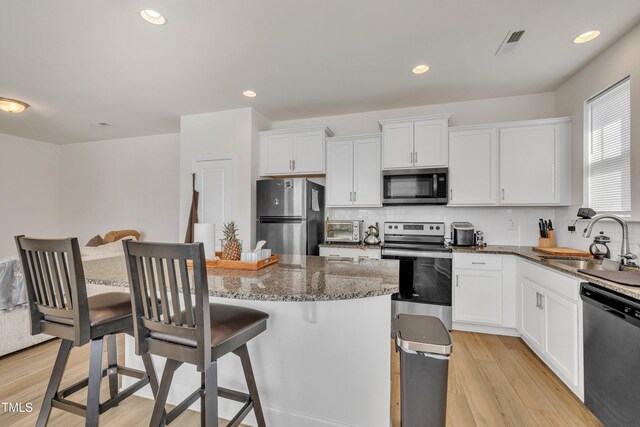 162 Channel Drop Dr, Clayton, NC 27520 - kitchen with visible vents, a kitchen breakfast bar, a sink, light wood-style flooring, and appliances with stainless steel finishes