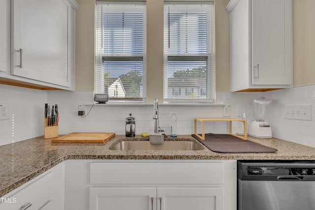 kitchen with stainless steel dishwasher, a sink, white cabinetry, and backsplash