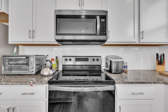 kitchen with decorative backsplash, appliances with stainless steel finishes, light stone countertops, a toaster, and white cabinets
