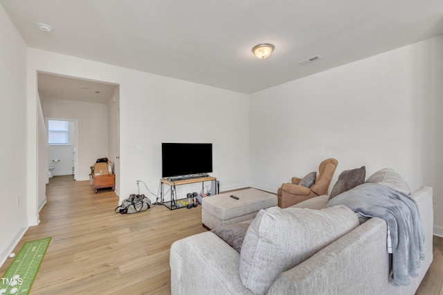 living area with baseboards, visible vents, and light wood-type flooring
