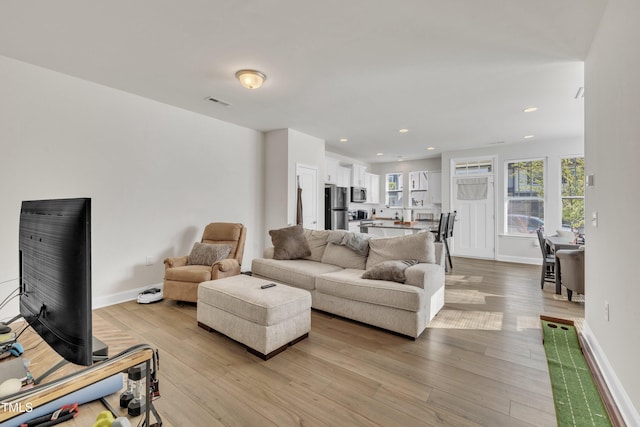 living area with recessed lighting, baseboards, and light wood finished floors