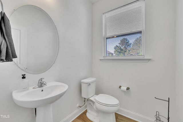 bathroom with a sink, baseboards, toilet, and wood finished floors