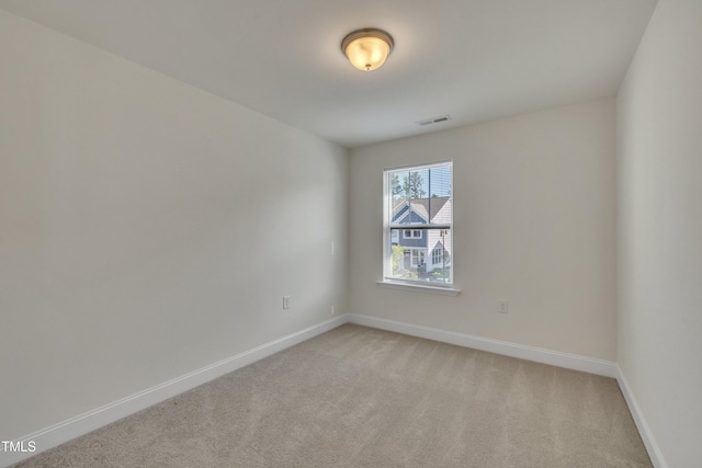 empty room featuring visible vents, baseboards, and light colored carpet
