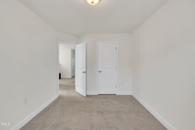 unfurnished room featuring baseboards and light colored carpet