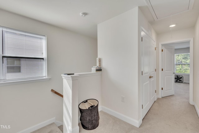 hallway featuring carpet floors, baseboards, an upstairs landing, and attic access