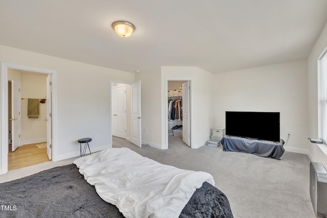 bedroom featuring baseboards, a walk in closet, carpet, and a closet