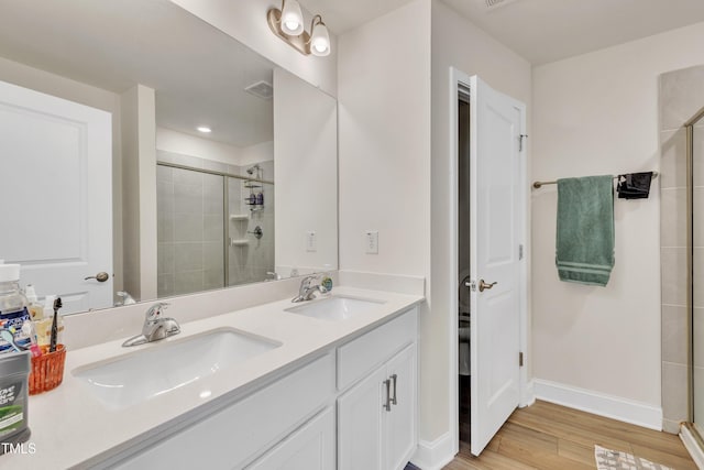 bathroom featuring a sink, a shower stall, and wood finished floors