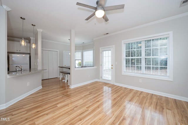 unfurnished living room featuring ceiling fan, baseboards, light wood-type flooring, visible vents, and ornamental molding