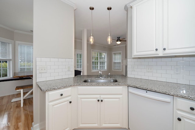kitchen featuring backsplash, crown molding, light wood-type flooring, dishwasher, and a sink
