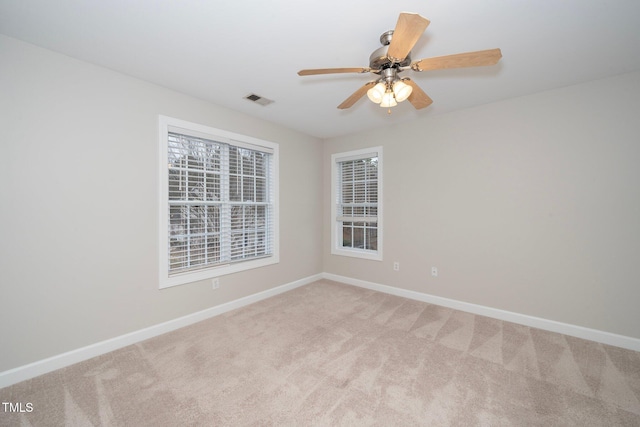 spare room featuring a ceiling fan, baseboards, visible vents, and light carpet