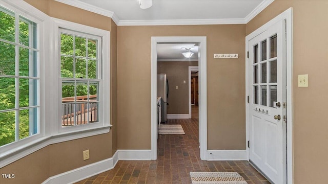 doorway with baseboards, ornamental molding, brick floor, and plenty of natural light