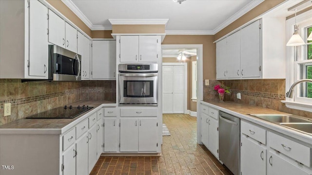 kitchen with brick floor, ornamental molding, decorative backsplash, white cabinets, and appliances with stainless steel finishes