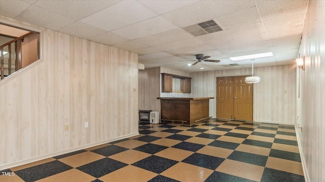 interior space featuring a paneled ceiling, dark floors, a ceiling fan, and visible vents