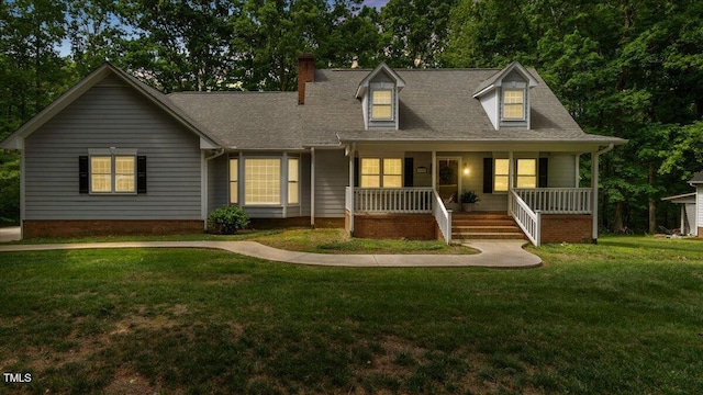 new england style home with a porch, a shingled roof, a front lawn, and a chimney