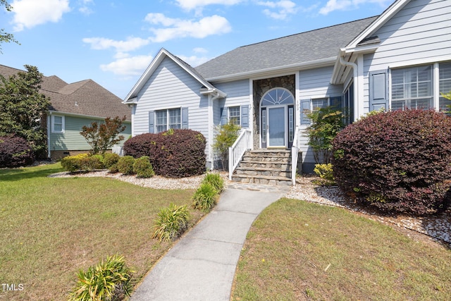 view of front of home with a front yard, roof with shingles, and entry steps