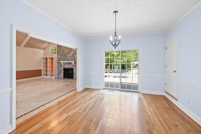 unfurnished dining area featuring a chandelier, wood finished floors, a fireplace, a textured ceiling, and baseboards