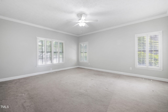 carpeted empty room with a ceiling fan, crown molding, and baseboards