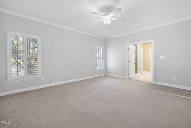 spare room featuring ornamental molding, light carpet, a ceiling fan, and baseboards
