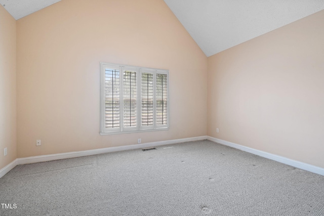 carpeted spare room featuring baseboards and high vaulted ceiling