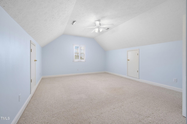 bonus room with a ceiling fan, light carpet, a textured ceiling, baseboards, and vaulted ceiling