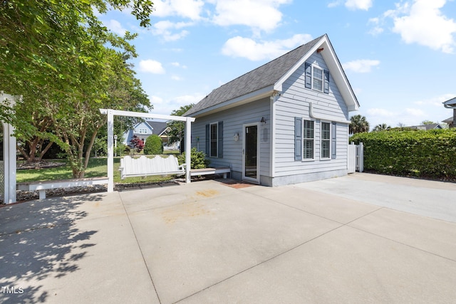 view of front facade with a patio area, driveway, and roof with shingles