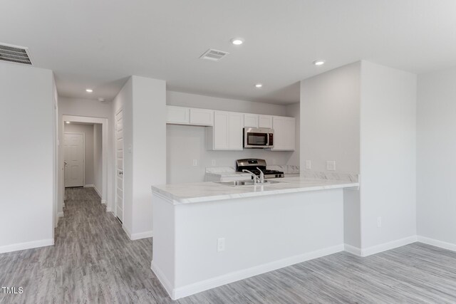 124 Landon Pl, Roxboro, NC 27573 - kitchen with white cabinets, light wood finished floors, light countertops, stainless steel appliances, and visible vents