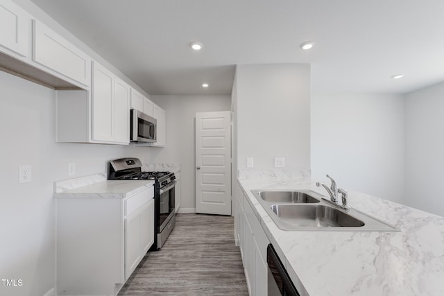 124 Landon Pl, Roxboro, NC 27573 - kitchen with appliances with stainless steel finishes, light wood-type flooring, a sink, a peninsula, and white cabinetry