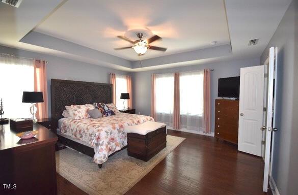 3032 Curling Creek Dr, Apex, NC 27502 - bedroom featuring multiple windows, wood finished floors, and a raised ceiling