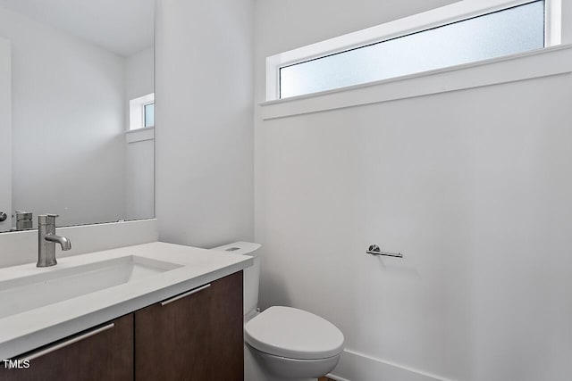 bathroom with healthy amount of natural light, toilet, and vanity