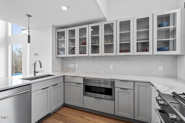 kitchen featuring appliances with stainless steel finishes, a sink, gray cabinetry, light stone countertops, and recessed lighting