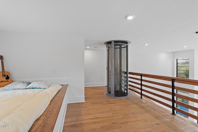 corridor featuring light wood finished floors, recessed lighting, and baseboards