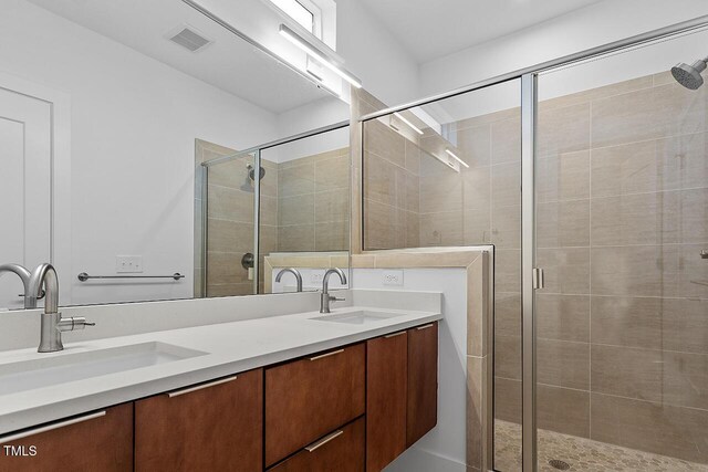 bathroom with a shower stall and double vanity